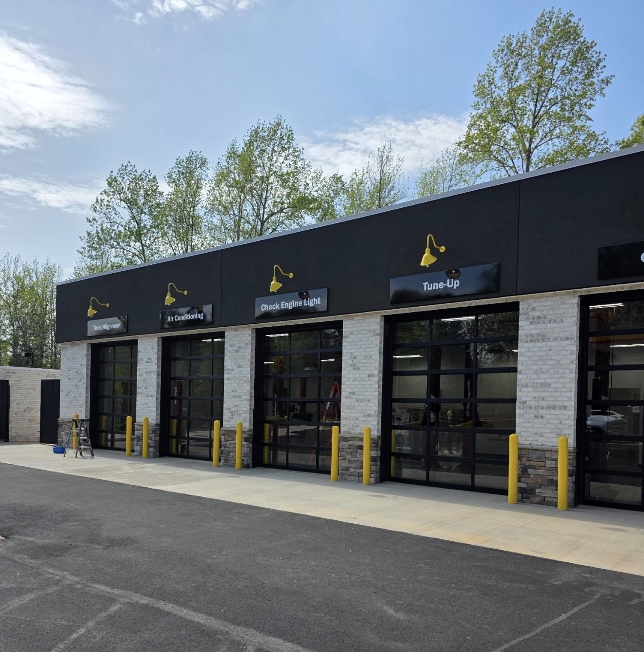 Four full-view glass garage doors with black frames at a commercial auto service center